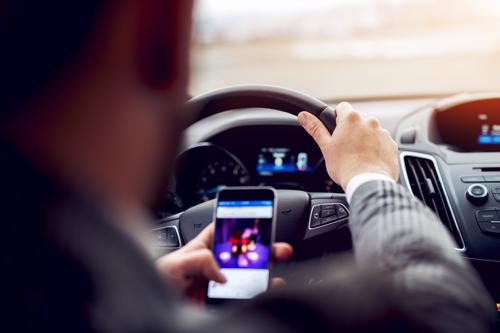 A man watching a video on his phone when driving.